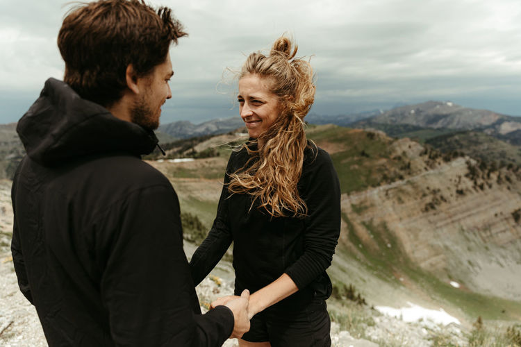 Woman awkward but happy, smiles during a surprise mountain engagement