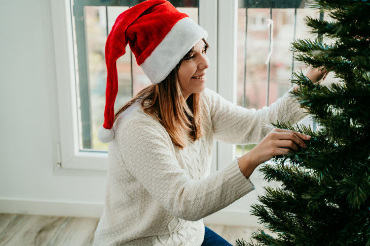 Midsection of woman with christmas tree at home