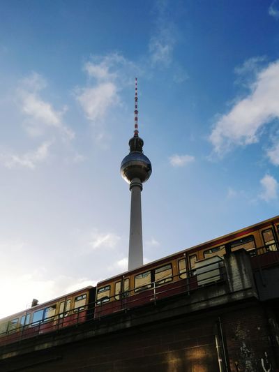 Low angle view of berlin tv communications tower and train against sky