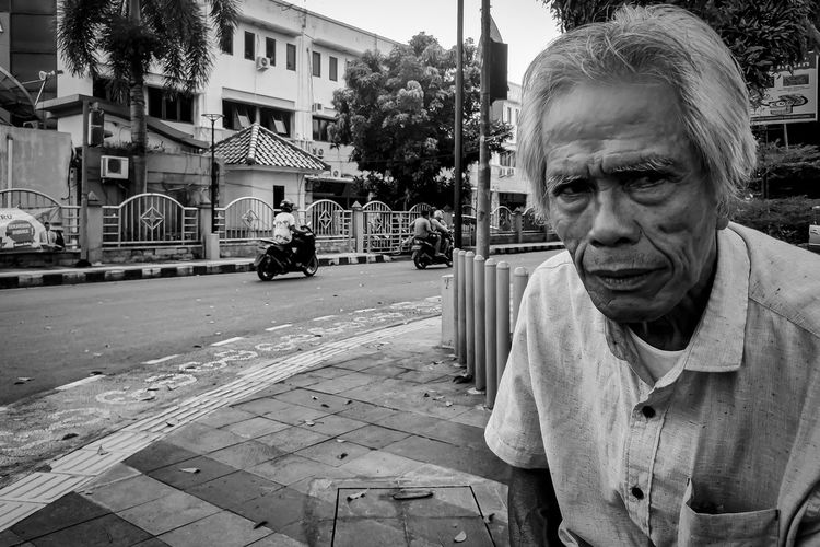 Portrait of man on street against buildings in city