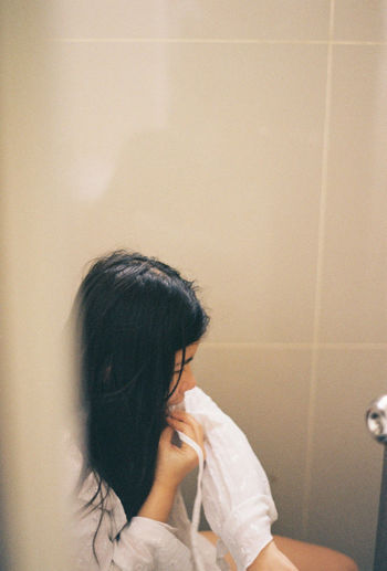 High angle view of young woman sitting in bathroom