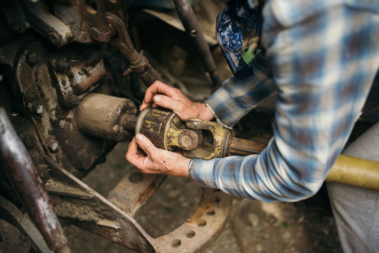 A mechanic is repairing a tractor used in agriculture closeup.
