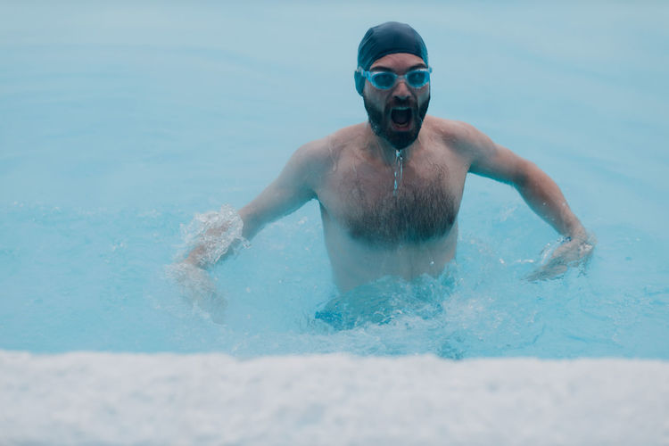 Shirtless man swimming in water