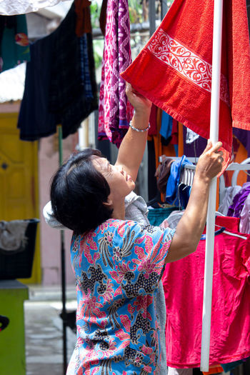 Rear view of woman standing against multi colored umbrella