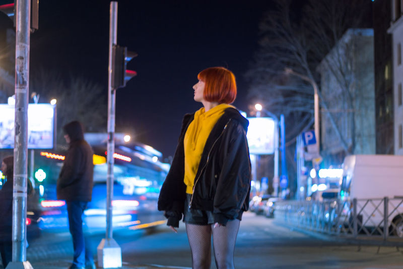 Rear view of women standing on illuminated street at night