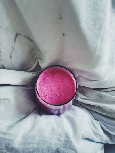 Close-up of a pink smoothie in bed