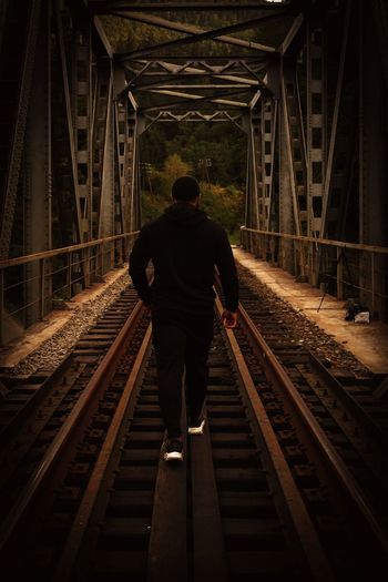 Rear view of man walking on railroad bridge