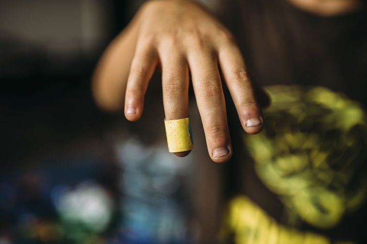 Cropped image of boy showing bandage on finger at home