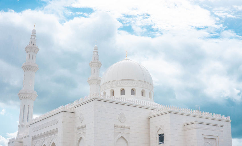 Low angle view of mosque against cloudy sky