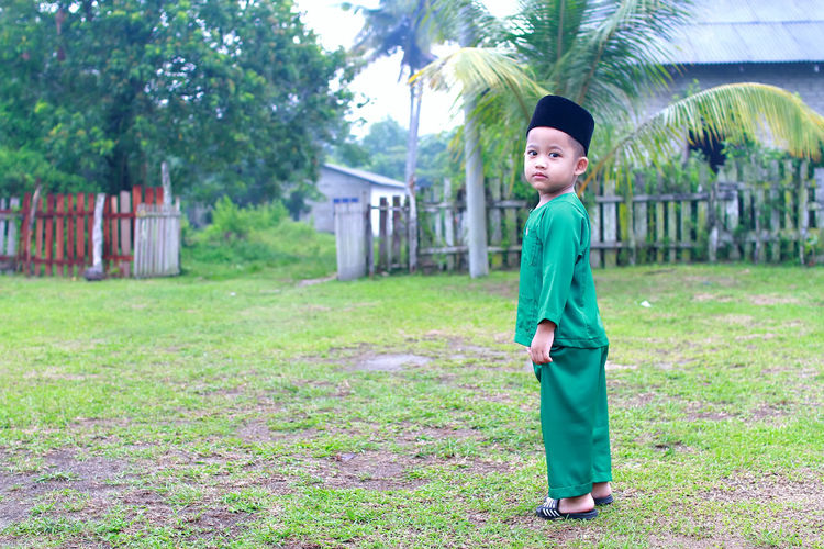 Full length portrait of boy in traditional clothing standing on field
