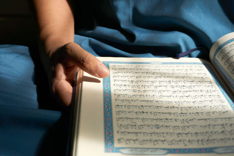 Midsection of muslim man reading quran
