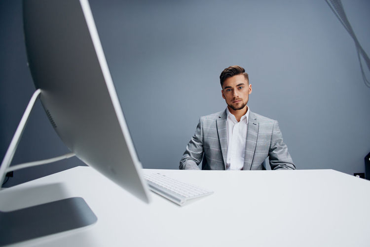 Portrait of businessman using laptop while standing in office