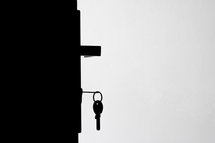 Close-up of key hanging on door against wall