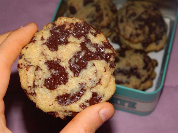 Close-up of cropped hand holding chocolate chip cookie at home