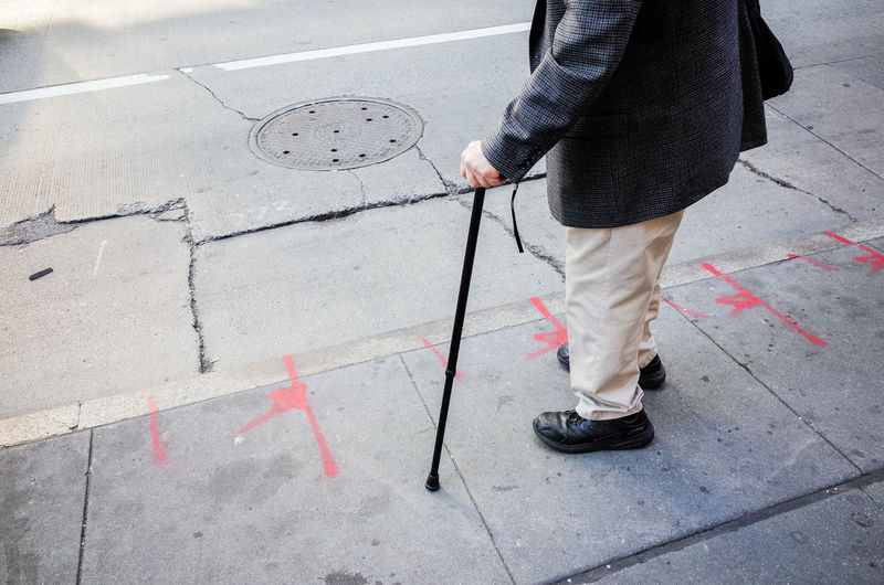 Single person walking across the street while using a cane walking stick in new york city