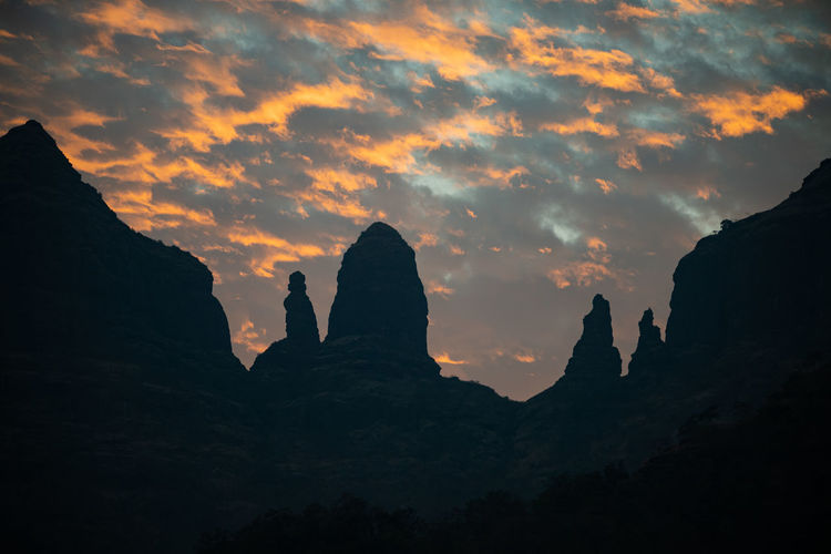 Silhouette rock formations against sky during sunset