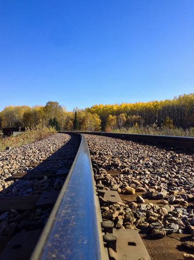 Surface level of railroad tracks against clear blue sky
