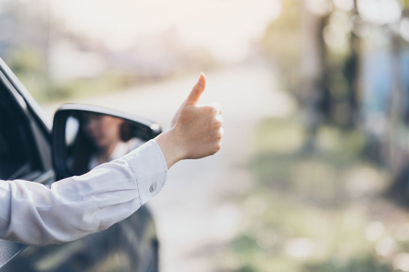 Woman showing thumbs up while traveling in car