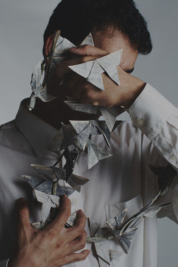 Portrait of man and origami butterflies against white background