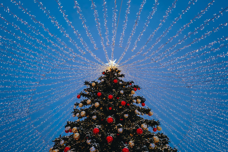 Low angle view of illuminated christmas tree against sky