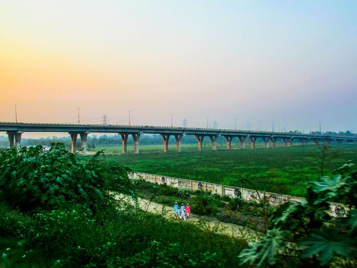 Bridge over field against sky during sunset