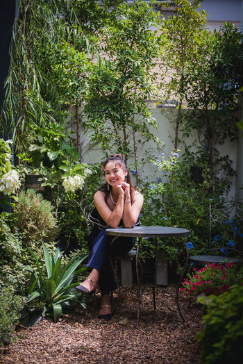 Portrait of woman sitting against plants