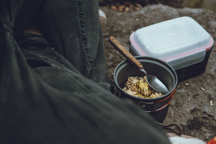 Midsection of person sitting by noodles in bowl