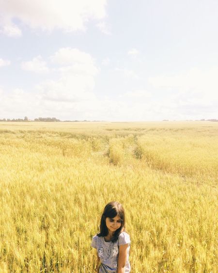 High angle view of woman standing in field against cloudy sky on sunny day