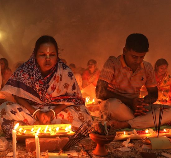Praying at rakher upobash infront of burning candle and incense