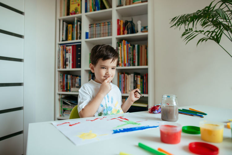 Boy doing painting while sitting at home