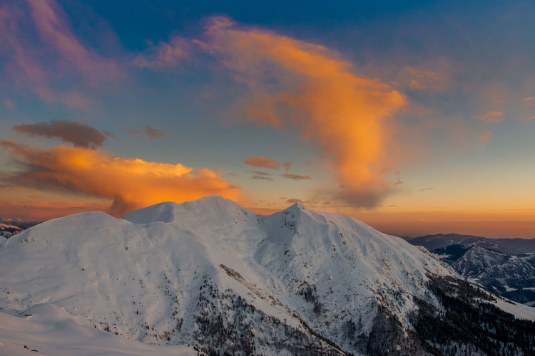 Snowy mountain with clouds at sunset