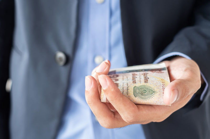 Midsection of businessman holding paper currencies