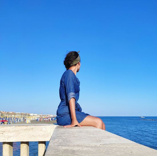 Woman looking at the beach against clear blue sky