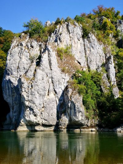 Rock formation by lake against sky