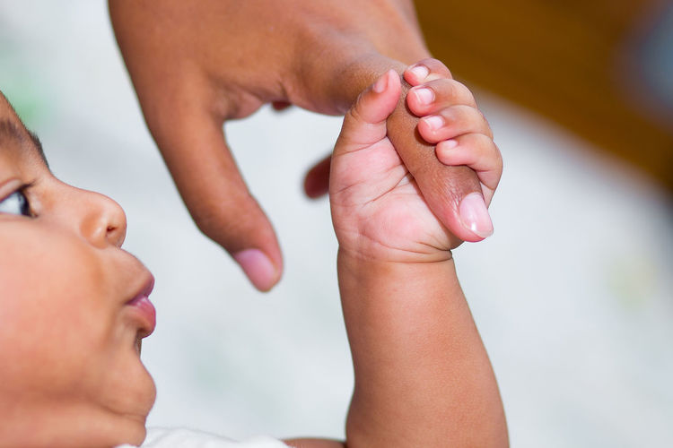Close-up of baby boy holding mother finger