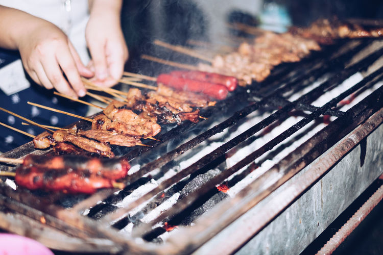 Cropped hands preparing food on barbecue grill