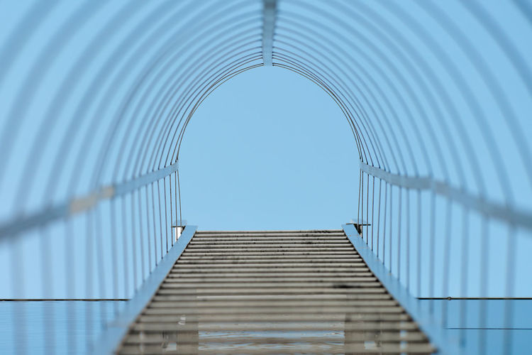 Fire escape staircase. long metal staircase on blue glass facade of office, industrial building
