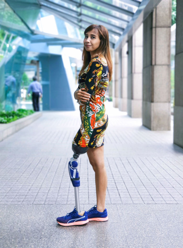 Full length portrait of woman with prosthesis leg standing on footpath