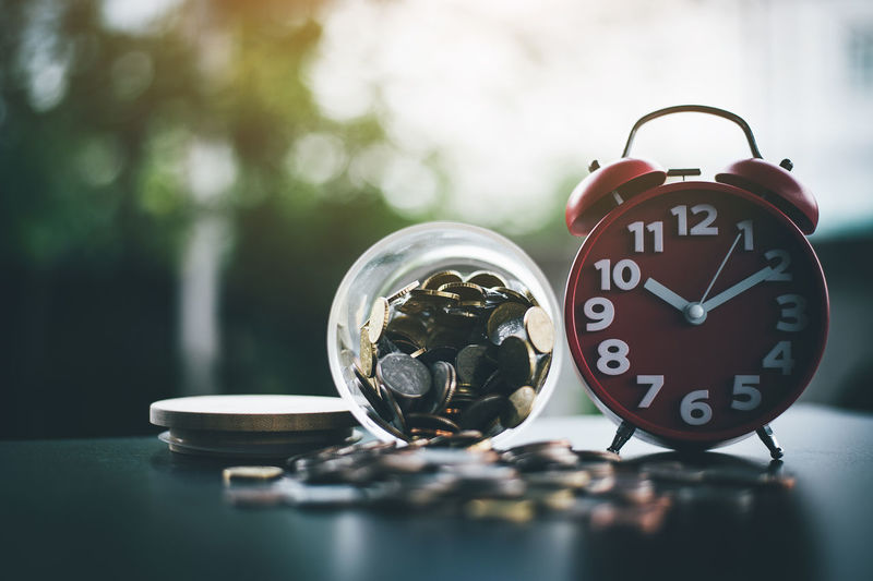 Coins spilling by alarm clock on table