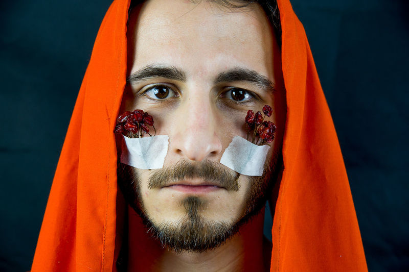 Close-up portrait of man wearing headscarf with dry cherries on cheeks