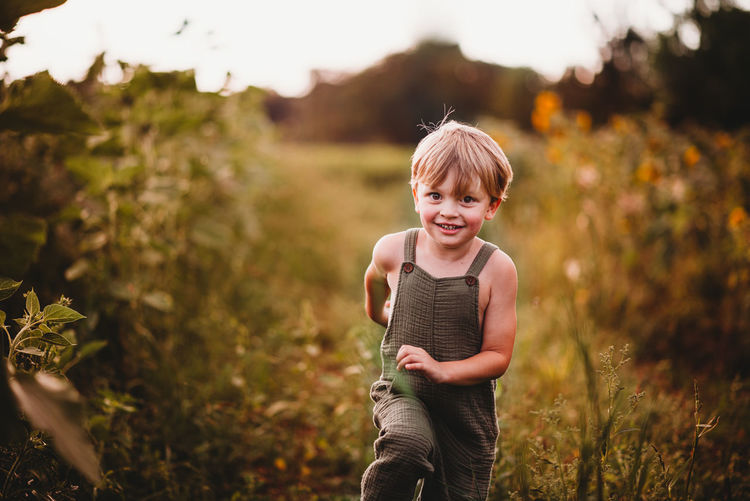 Happy boy running in a flower field wearing green dungarees