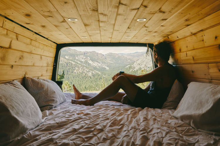 Young man on bed of camper van watching views of yosemite park.