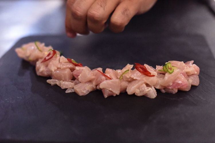 Cropped hand garnishing sushi on slate in kitchen