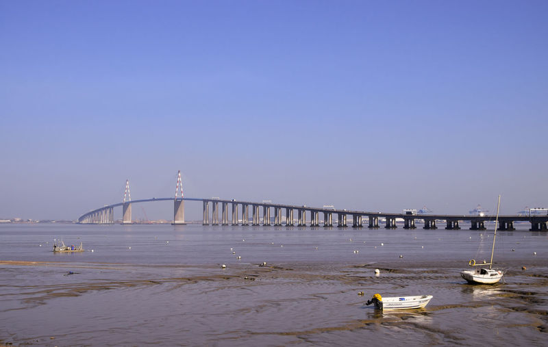 Bridge over sea against clear blue sky