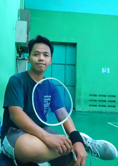 Portrait of young man sitting down after badminton 