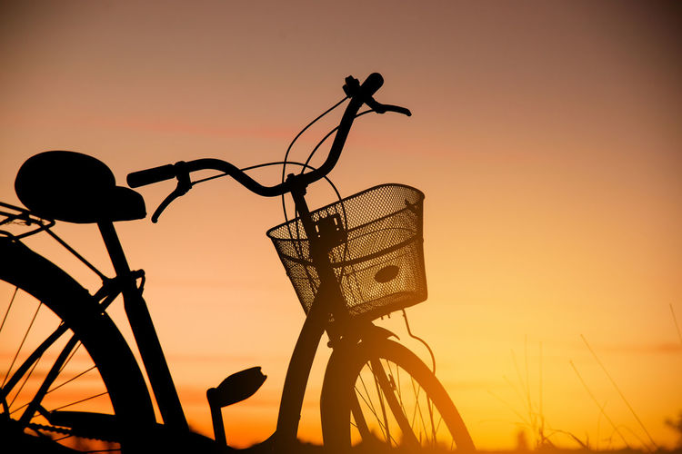 Close-up of silhouette bicycle against orange sky
