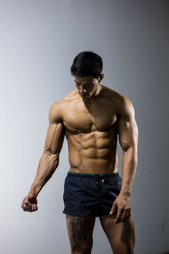 Shirtless muscular man standing against wall