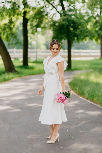 Full length of woman standing holding bouquet in park