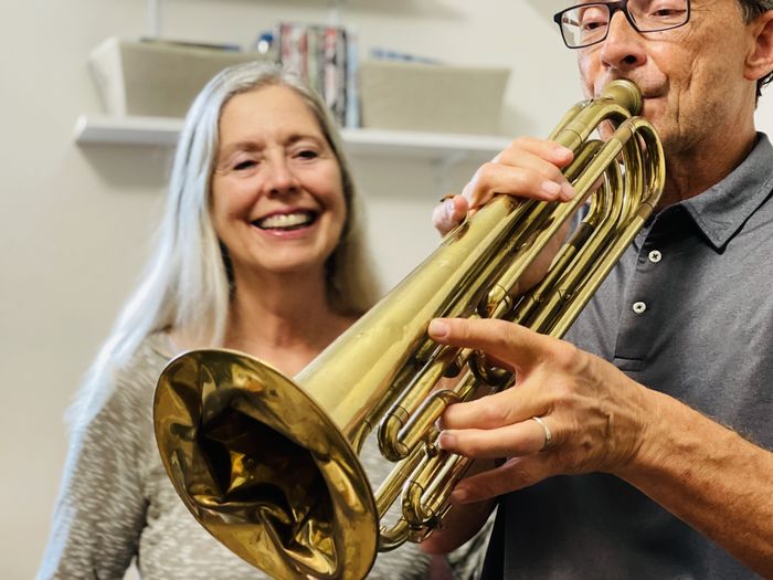 Active seniors couple with man playing bugle and woman smiling with enjoyment.  portrait.   