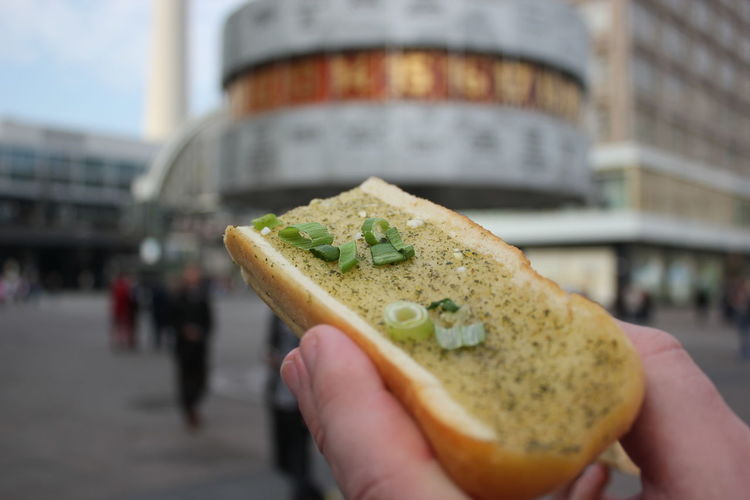 Cropped image of hand holding garlic bread on city street